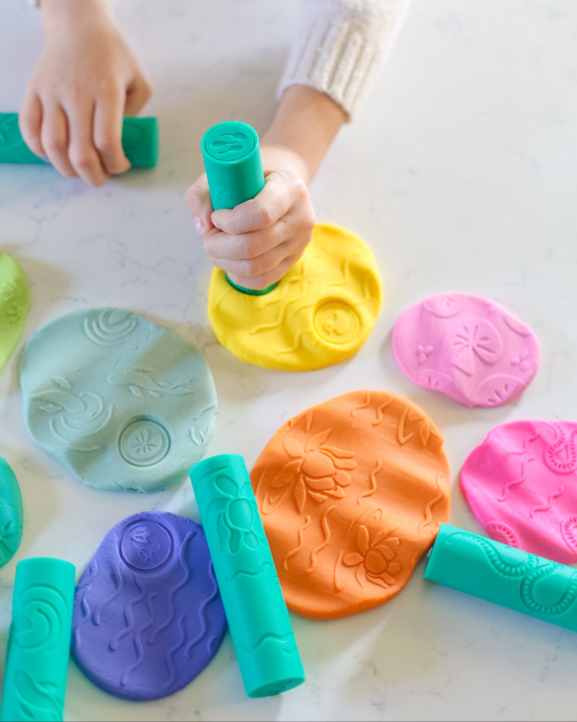 Colorful play dough with child's hands interacting on a light surface