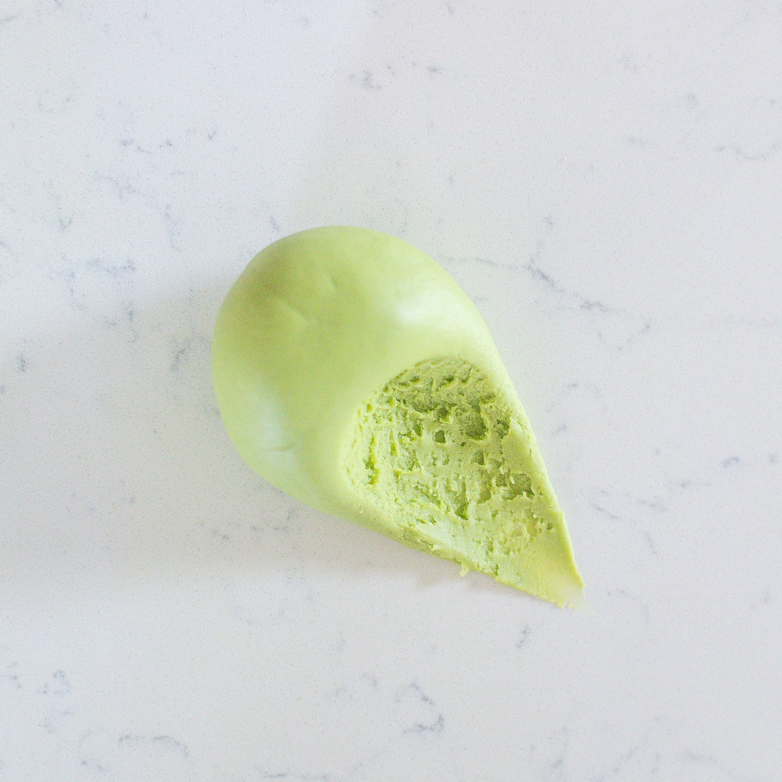 A light green ball of soft play dough placed on a white marble surface.
