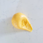 A small dollop of smooth yellow play dough sits on a light marble-like surface.