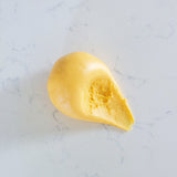 A small dollop of smooth yellow play dough sits on a light marble-like surface.
